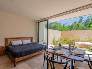 ein Schlafzimmer mit einem Bett und einem Tisch mit Stühlen in der Unterkunft Peregrina Tulum 110 1BR Condo with Jacuzzi in Tulum
