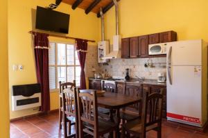 eine Küche mit einem Tisch und einem weißen Kühlschrank in der Unterkunft Ñanderoga Bungalows in Colón