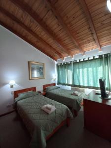 um quarto com duas camas, uma escrivaninha e uma janela em Hotel Antartida Argentina em Ushuaia