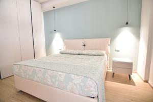 ein weißes Schlafzimmer mit einem Bett und einem Nachttisch in der Unterkunft Ti porto al mare in Marina di Ragusa