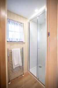 ein Bad mit einer Dusche und einem weißen Handtuch in der Unterkunft Friels Fairy Tree Hawthorn lodge in Swatragh