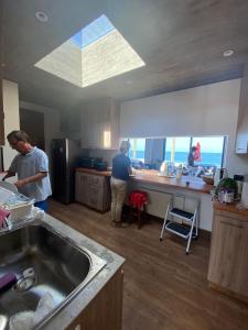 twee mensen die in een keuken eten klaarmaken bij Increíble casa primera lineal Playa Morrillos in La Hacienda