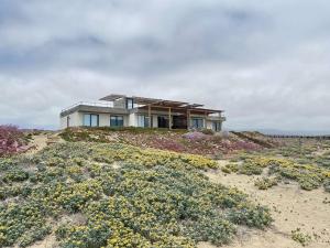 een huis bovenop een heuvel met bloemen bij Increíble casa primera lineal Playa Morrillos in La Hacienda