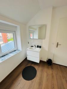 un piccolo bagno con lavandino e finestra di L'R du Phare maison à 150 mètres de la plage a Gravelines