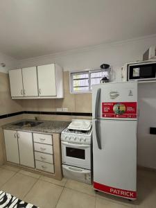 a kitchen with white cabinets and a white refrigerator at Beach House and Nature in Aguas Verdes