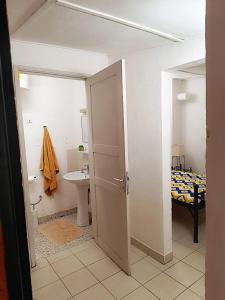 una habitación con un baño con lavabo y una cama en Hôtel Les Palmiers, en Ouagadougou