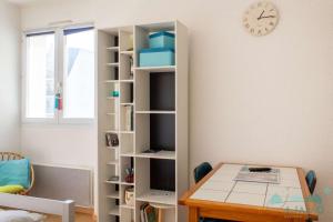 Una estantería con una mesa y un reloj en la pared. en 104 - Studio, dans une résidence les pieds dans l'eau à Sables D'or Les Pins, en Sables-dʼOr-les-Pins