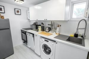 圣安德烈Bükkös Liget Apartman的带洗衣机和水槽的白色厨房