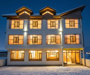 a building with illuminated windows in the snow at Gulmarg GS Residency Hotel in Gulmarg