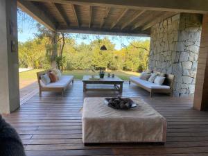 patio con divani e tavolo su una terrazza in legno di Casa de Piedra Village del Faro a José Ignacio