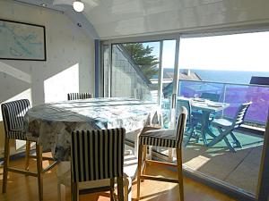 a dining room with a table and chairs and a balcony at Appartement 4 à 6 personnes avec vue mer - GWENAEL in Sarzeau
