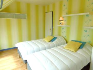 two beds in a room with yellow walls at Appartement 4 à 6 personnes avec vue mer - GWENAEL in Sarzeau