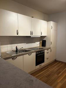een keuken met witte kasten en een spoelbak bij Wümme Apartment in Rotenburg an der Wümme +2 foto's