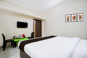 a bedroom with a bed and a desk with a television at Hotel O AMRITA PREMIUM in Bhubaneshwar