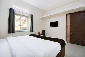 a bedroom with a large white bed and a television at Hotel O AMRITA PREMIUM in Bhubaneshwar
