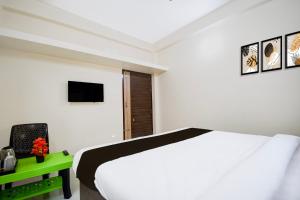 a white bedroom with a bed and a television at Hotel O AMRITA PREMIUM in Bhubaneshwar +23 photos