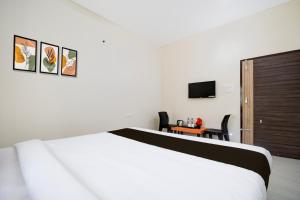 a bedroom with a bed and a desk and a television at Hotel O AMRITA PREMIUM in Bhubaneshwar