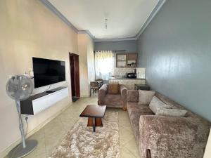 a living room with a couch and a flat screen tv at Aurora two in Kampala