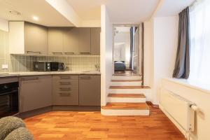 塔林Old Town - Best Location Apartment的通往厨房的楼梯,厨房配有白色橱柜 更多14张照片