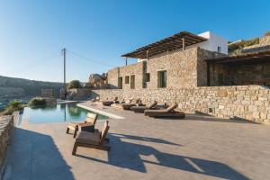 a resort with a row of chairs and a pool at Villa Altheon Mykonos in Mykonos