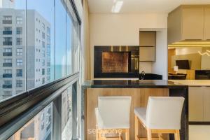 una camera con balcone con 2 sedie e cucina di Aptos em prédio a 90 m da praia de Perequê - RIHs a Perequê