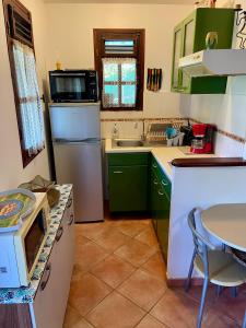 a kitchen with green cabinets and a white refrigerator at Les Sucriers in Les Anses-dʼArlets