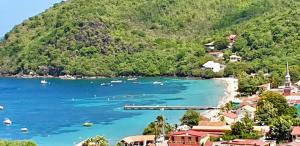 a view of a beach with houses and a mountain at Les Sucriers in Les Anses-dʼArlets