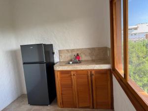 a kitchen with a refrigerator and a sink and a window at Casa del Sol Holbox - Self Check In in Holbox Island