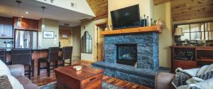 a living room with a stone fireplace and a bar at Utopia at Rundle Cliffs Lodge in Canmore