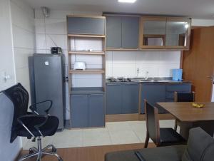 uma cozinha com armários azuis, uma mesa e um frigorífico em Apartamento dentro da ucs universidade em Caxias do Sul mais 6 fotografias