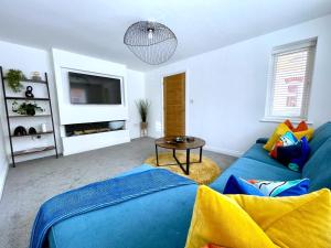グロスターにあるBrand NEW 4-bedroom detached house - 20-min walk to Gloucester Docks - Ample Parking - Superfast Wi-Fi - Long-stay rates!の青いソファとテレビのあるリビングルーム