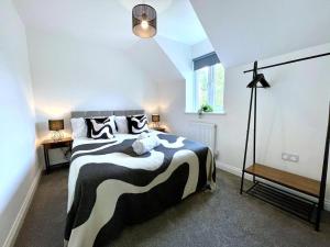 グロスターにあるBrand NEW 4-bedroom detached house - 20-min walk to Gloucester Docks - Ample Parking - Superfast Wi-Fi - Long-stay rates!のベッドルーム(白黒のベッド、ランプ付)