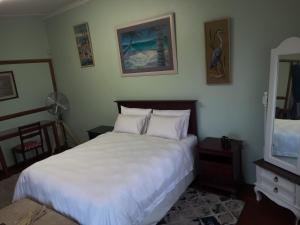 a bedroom with a large white bed and a mirror at 83 Ocean View in Port Shepstone