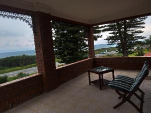 a porch with a chair and a table on it at 83 Ocean View in Port Shepstone
