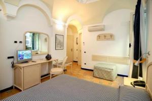 a room with a bed, a desk and a television at Hotel Bellevue Suite in Amalfi