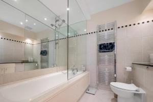 a bathroom with a tub and a toilet and a sink at Stylish Kensington Apartments in London +22 photos