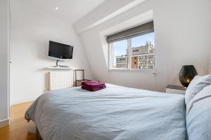 a bedroom with a bed and a tv on the wall at Stylish Kensington Apartments in London