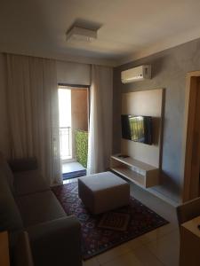 a living room with a couch and a television at Flat Hotel Mont Blanc Premium in Ribeirão Preto