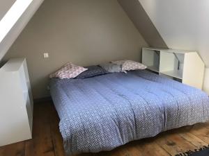 a bedroom with a bed with a blue comforter and pillows at Appartement duplex 180m² in La Bourboule