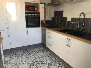 a kitchen with white cabinets and a tile floor at Appartement duplex 180m² in La Bourboule