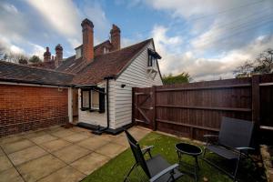 una piccola casa bianca con una recinzione e delle sedie di Charming 1 Bedroom Period Cottage in Sevenoaks a Chevening