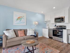a living room with a couch and a kitchen at Oceanview Bliss in Tybee Island