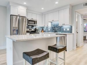 a kitchen with white cabinets and a large island with stools at Lazy Hammock in Tybee Island