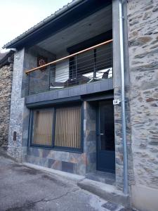 a brick building with a balcony and a door at Maison de Lily in Cier-de-Luchon