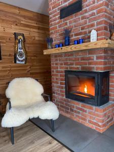 a brick fireplace with two white chairs and a fire place at Wilcza Chata in Polańczyk