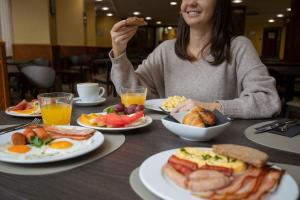 a woman sitting at a table with plates of breakfast food at Hotel Cervol by Nexta in Andorra la Vella