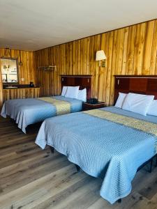 twee bedden in een kamer met houten wanden bij Country Inn - Licking in Licking