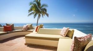 a patio with couches and a palm tree and the ocean at Casa Edwards II in San José del Cabo