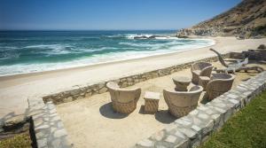 a beach with a row of stone chairs and the ocean at Casa Edwards II in San José del Cabo