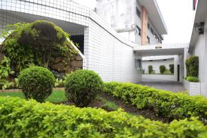 un jardín de arbustos y setos frente a un edificio en Carícia Hotel (Adult Only) en Santos